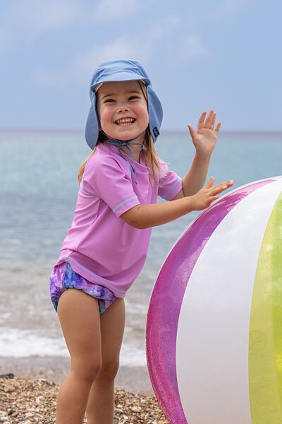 Usměvavá dívka v UV oblčení Playshoes v růžových a modrých barvách.